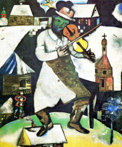The Fiddler by Marc Chagall, green face with crooked nose, one foot on small roof, buildings behind with snow on roofs.