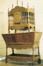 A panetiere, an openwork bread box made of wood spindles, sitting on a kneading table.
