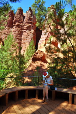 Susan Vreeland taking notes in the shade with ochre pinnacles behind her: Photo Copyright Marcia M. Mueller